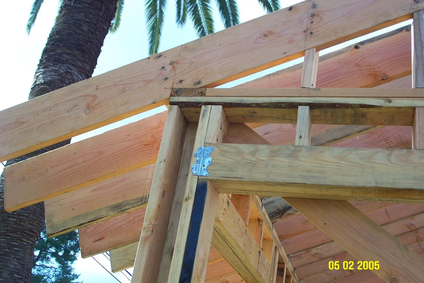 A wooden structure with some wood beams and a palm tree
