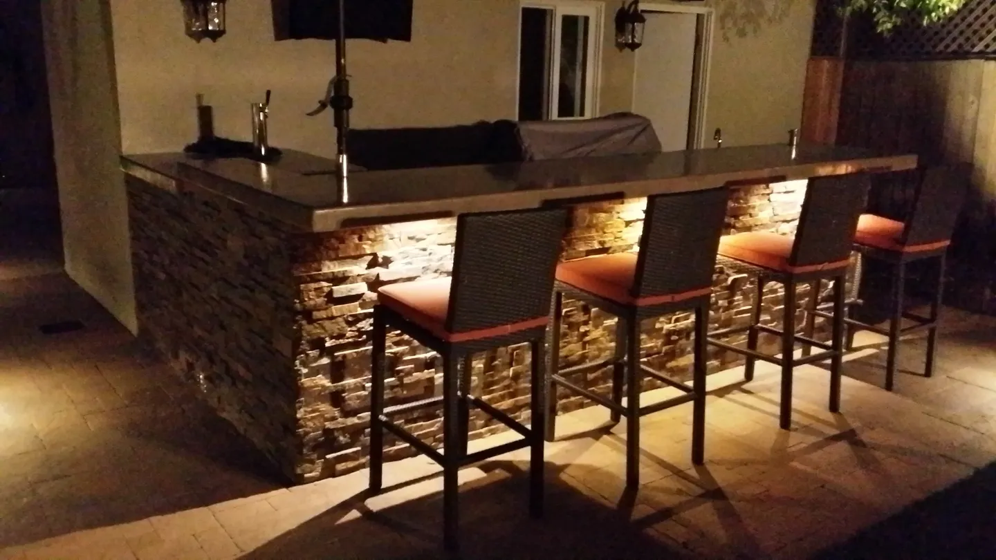 A bar with three chairs and lights on the wall